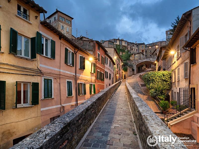 Perugia, Italy. Medieval aqueduct and colorful buildings at dusk