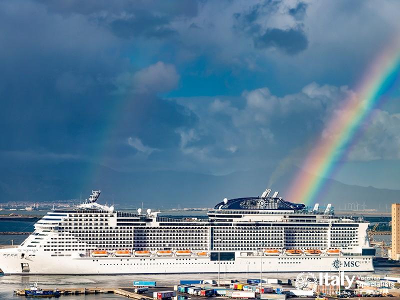 Cruise ship MSC Meraviglia moored on Cagliari harbor with a rainbow on background