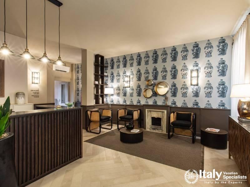 A stylish and inviting reception area with patterned wallpaper, warm lighting, and comfortable seati