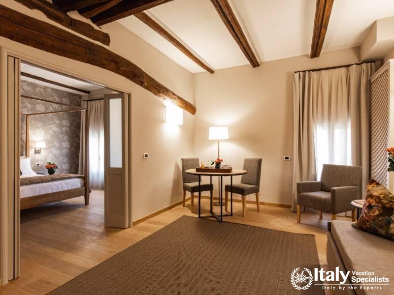 A spacious suite with exposed wooden beams and a separate seating area.