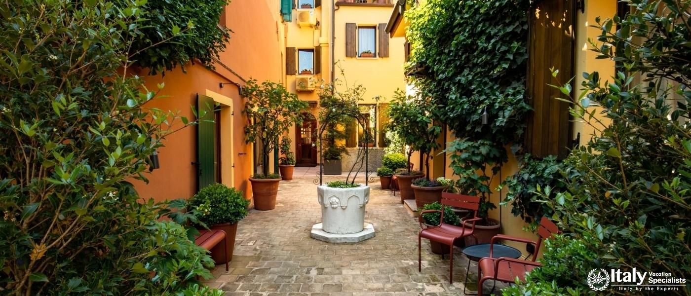 Relax in the tranquil courtyard surrounded by lush greenery and classic Italian architecture.
