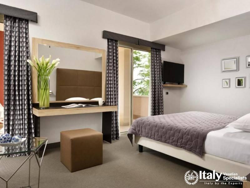 A stylish room with modern dÃ©cor, featuring soft lighting and a cozy bed, with access to a balcony 