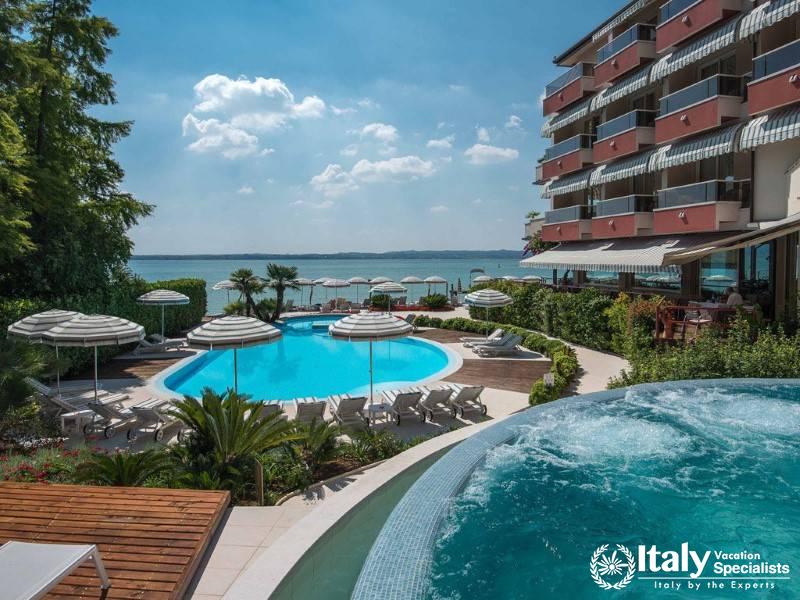 A picturesque outdoor pool area overlooking the lake, surrounded by lounge chairs and umbrellas.