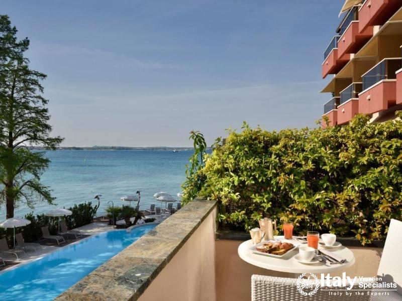 A serene balcony breakfast setup with stunning views of the pool and the sparkling blue lake beyond.