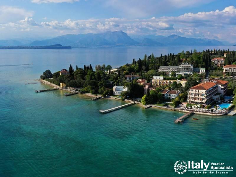 A scenic view of the hotel by the lakeside, surrounded by lush greenery and clear blue waters.