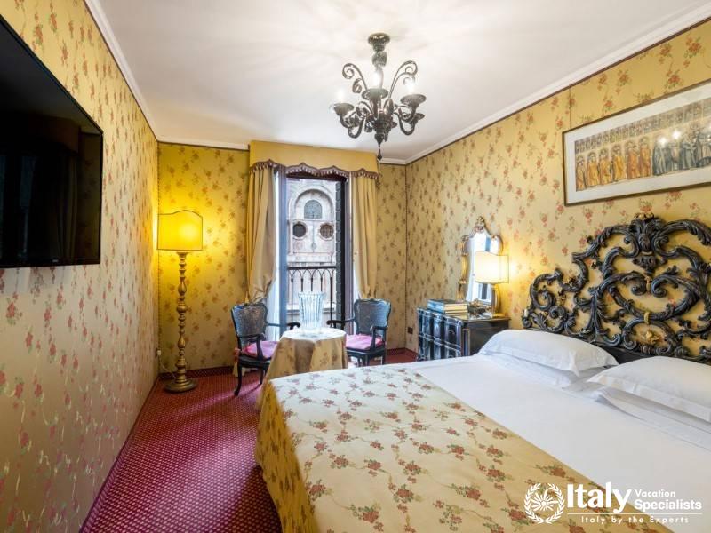 Cozy room with ornate furnishings and floral wallpaper, overlooking a historic building.