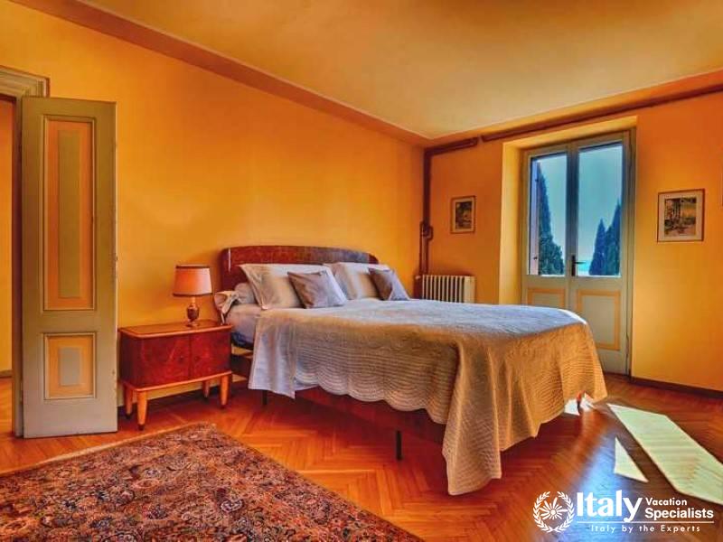 Restful Elegance: A comfortable bedroom with rich hues and tranquil lake vistas in Villa Elegante