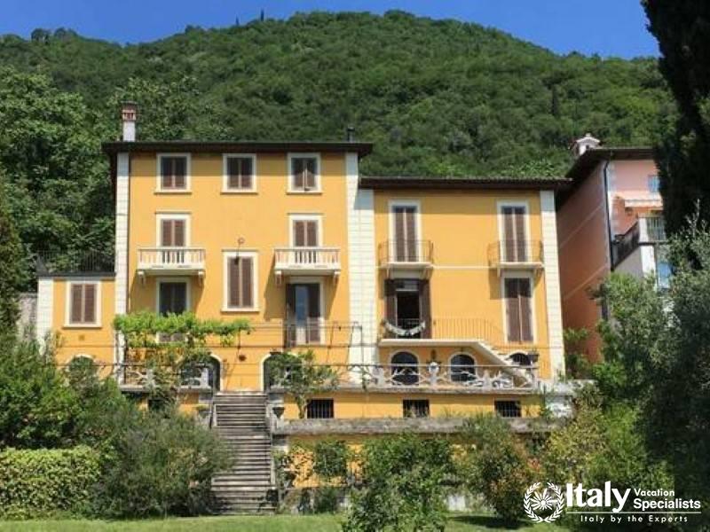 Classic Elegance: Stately yellow villa nestled in lush hillside greenery near lake Garda