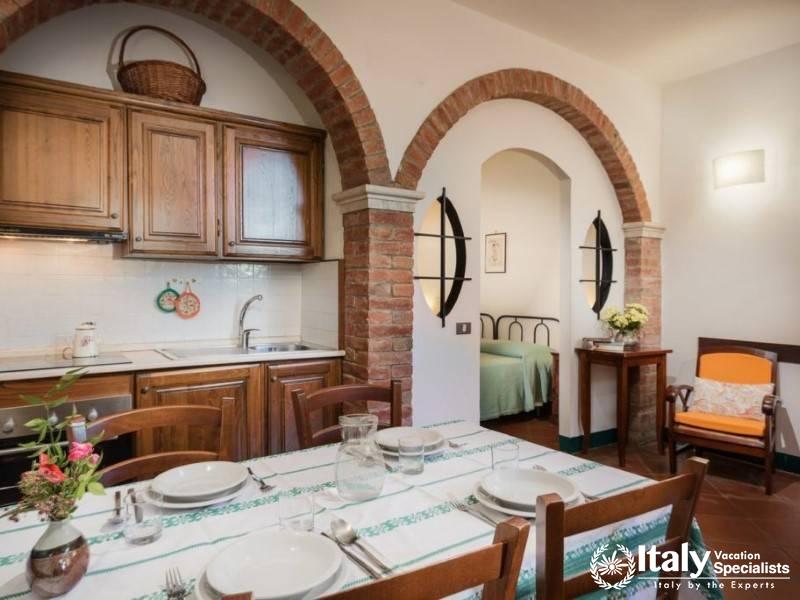 Dining and kitchen area with a view into the bedroom through a charming brick archway.