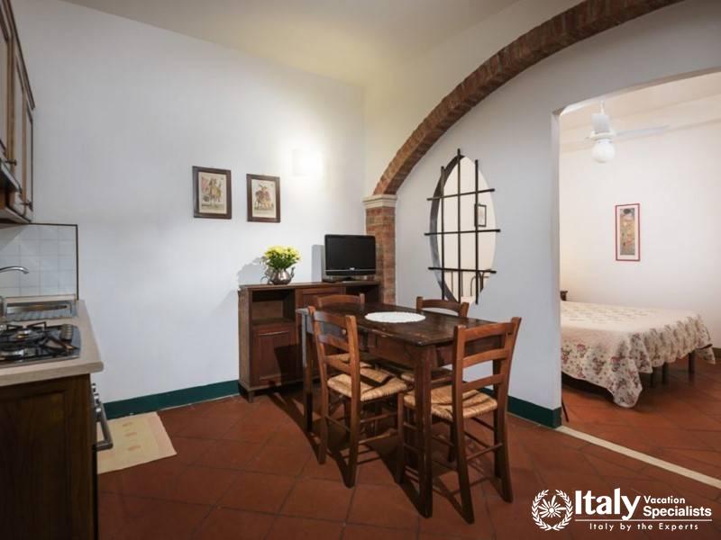 Open studio layout with kitchen, dining area, and visible bedroom space, all under a arch.