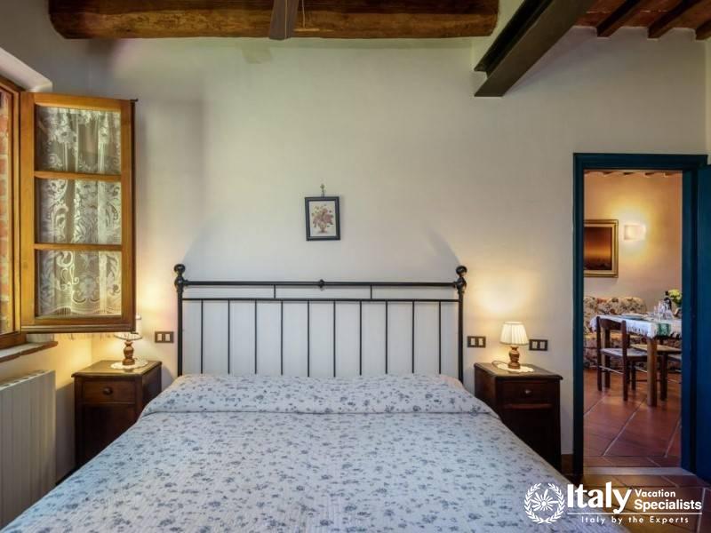 Comfortable bedroom with a view into the dining area through a doorway.