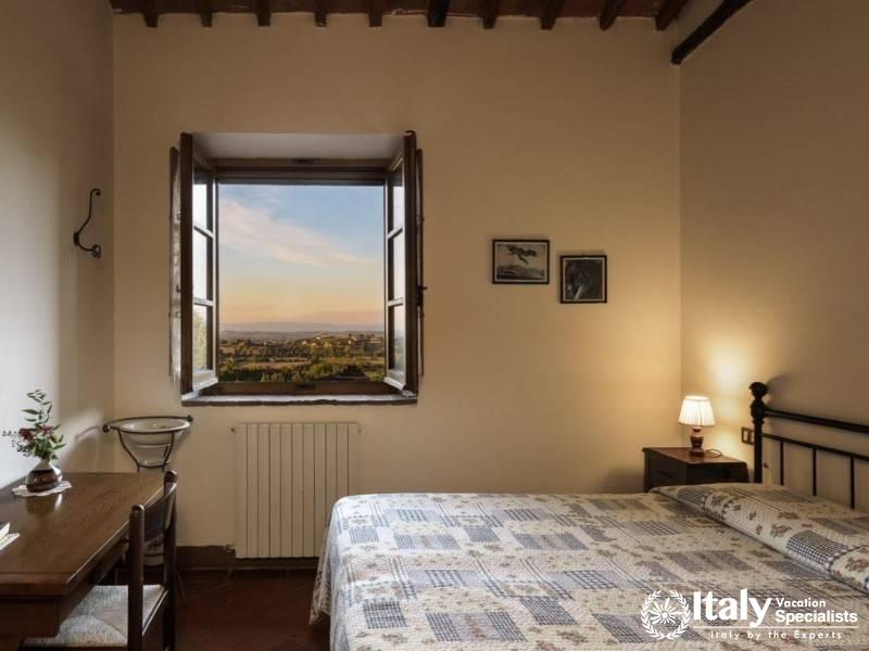 Bedroom with a picturesque window view of the sunset over the landscape.