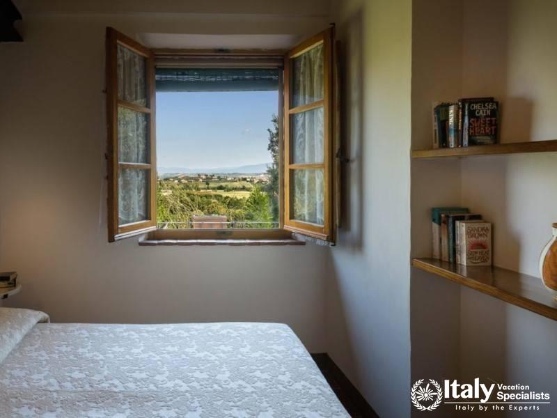 Bedroom with a view of the lush countryside through a charming window.