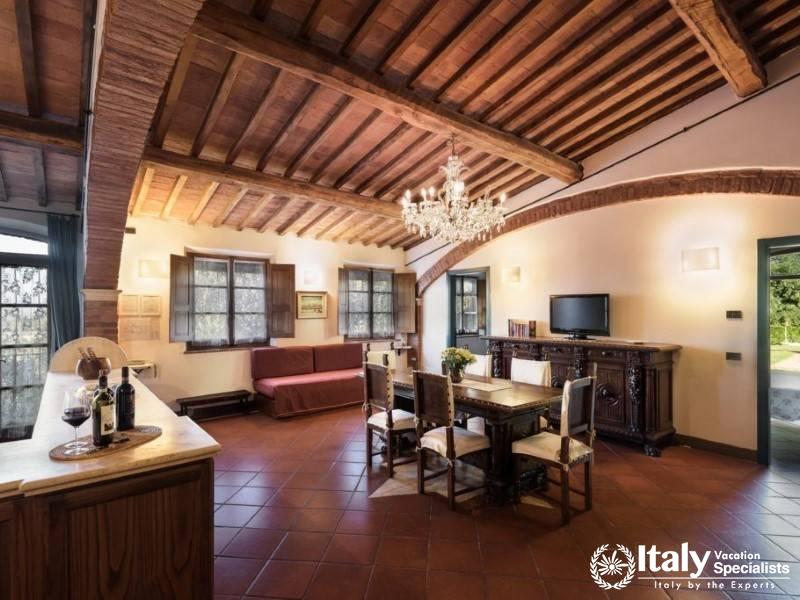 Rustic charm with wooden beams, a grand chandelier, and cozy seating by the window.