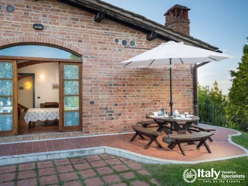 Wooden picnic table under an umbrella, set in a serene garden.