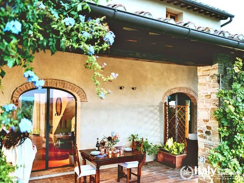 Outdoor dining area with flowering vines and arched doorway.