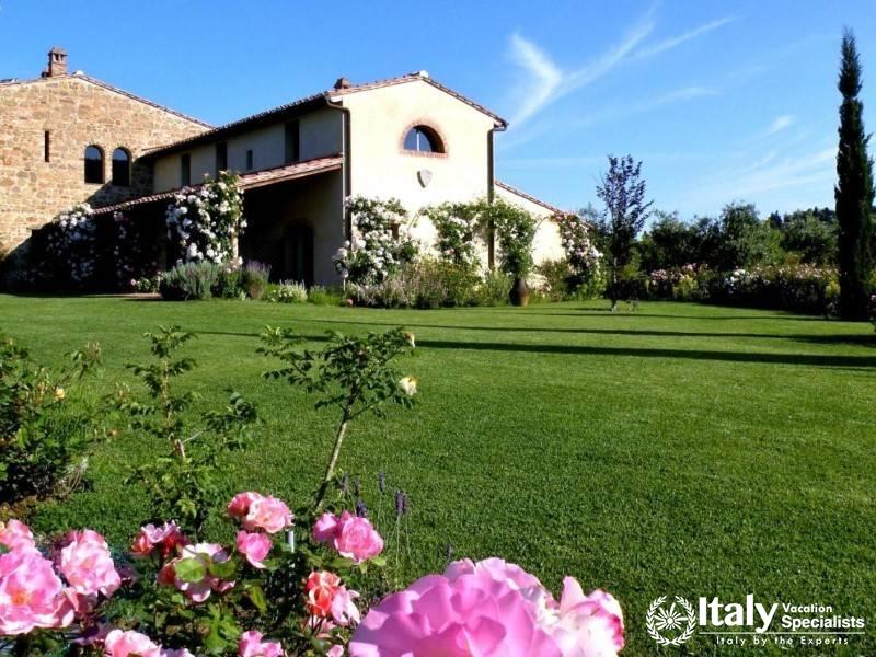 Stone villa surrounded by lush gardens and blooming roses.