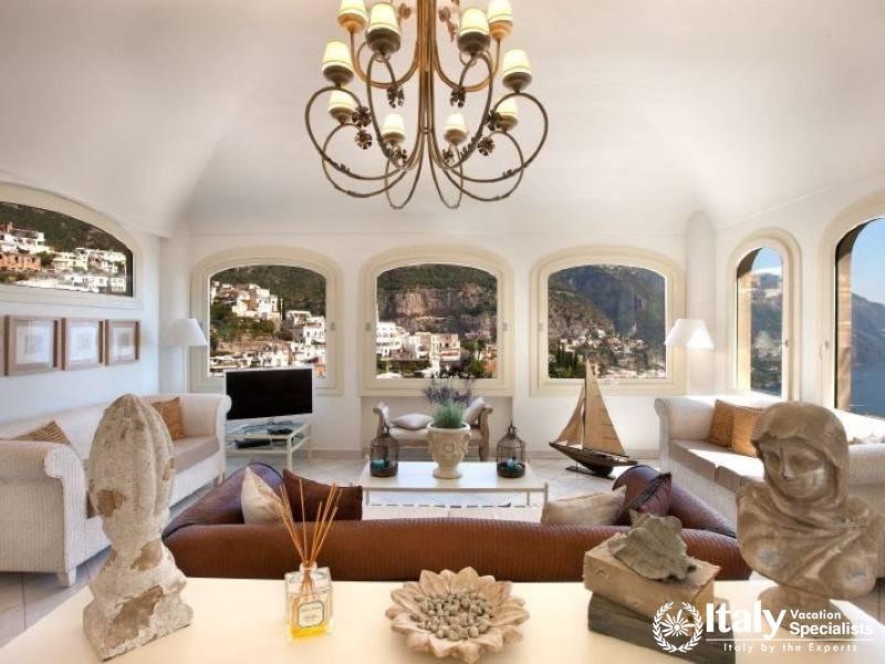 A luxurious living room featuring large windows with captivating views of Positano.