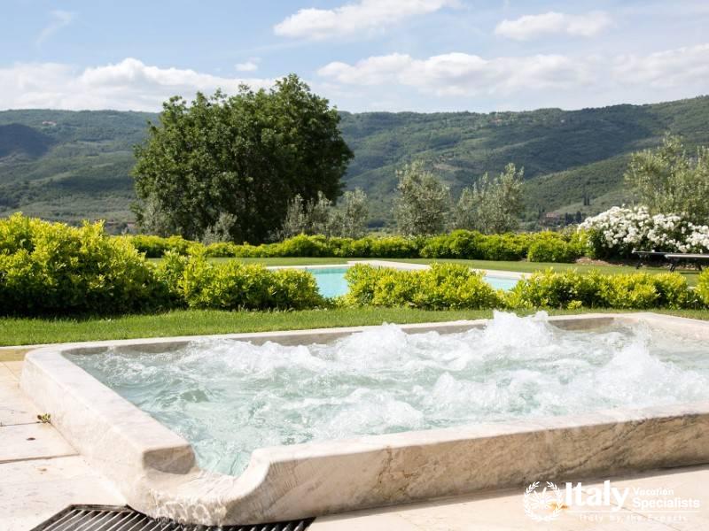 Outdoor jacuzzi with panoramic views of lush greenery.