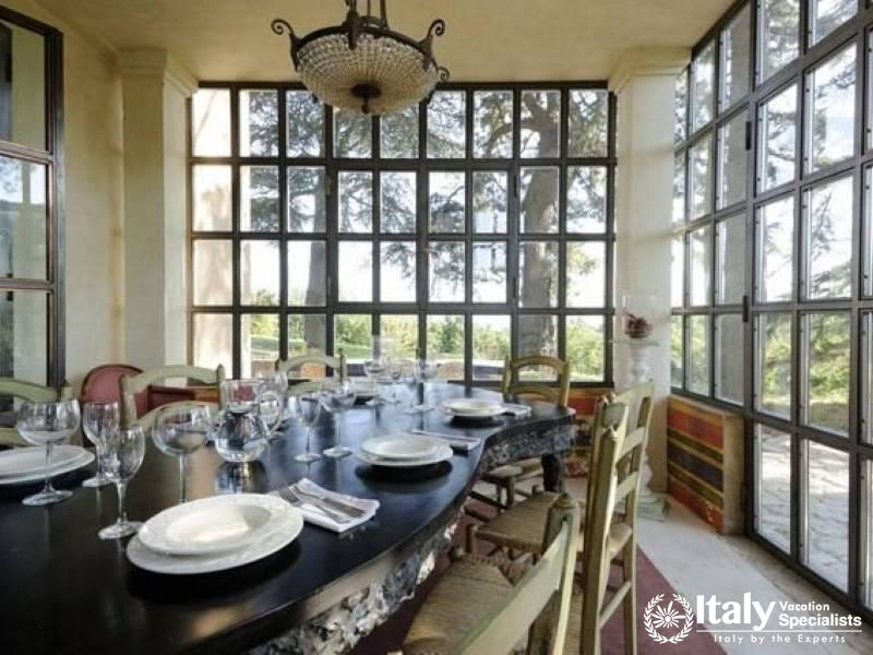 Dining room with large windows and a long table set for a meal.