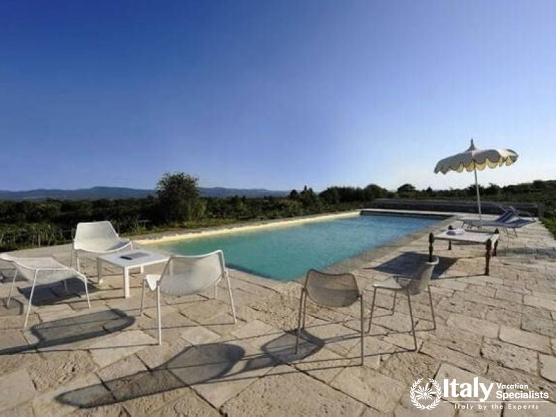 Outdoor pool area with lounge chairs and an umbrella.
