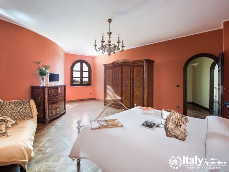 Spacious master bedroom with vintage furnishings and a classic chandelier.