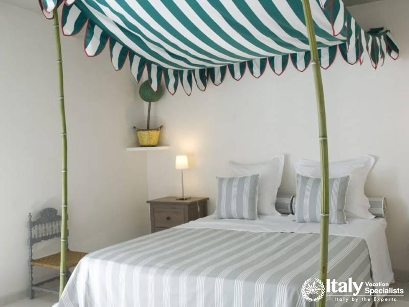 A charming bedroom with a striped canopy bed at Villa Sole di Marsala.