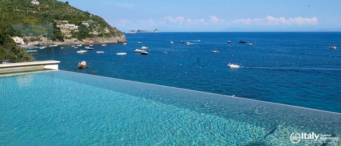 Infinity pool overlooking a serene bay with boats.