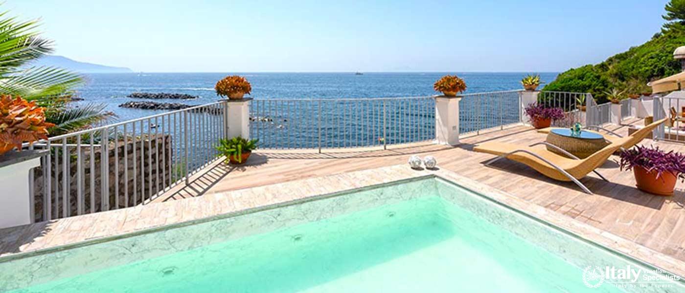 A refreshing pool overlooking the serene sea, framed by a spacious deck.