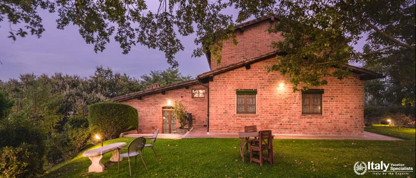 A tranquil evening view of a brick house with manicured lawns and outdoor seating.