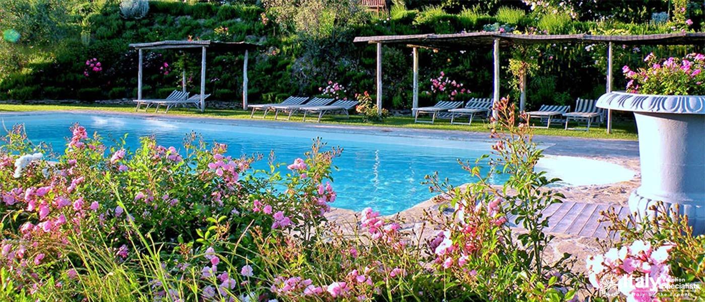 Poolside surrounded by colorful flowers and shaded loungers.