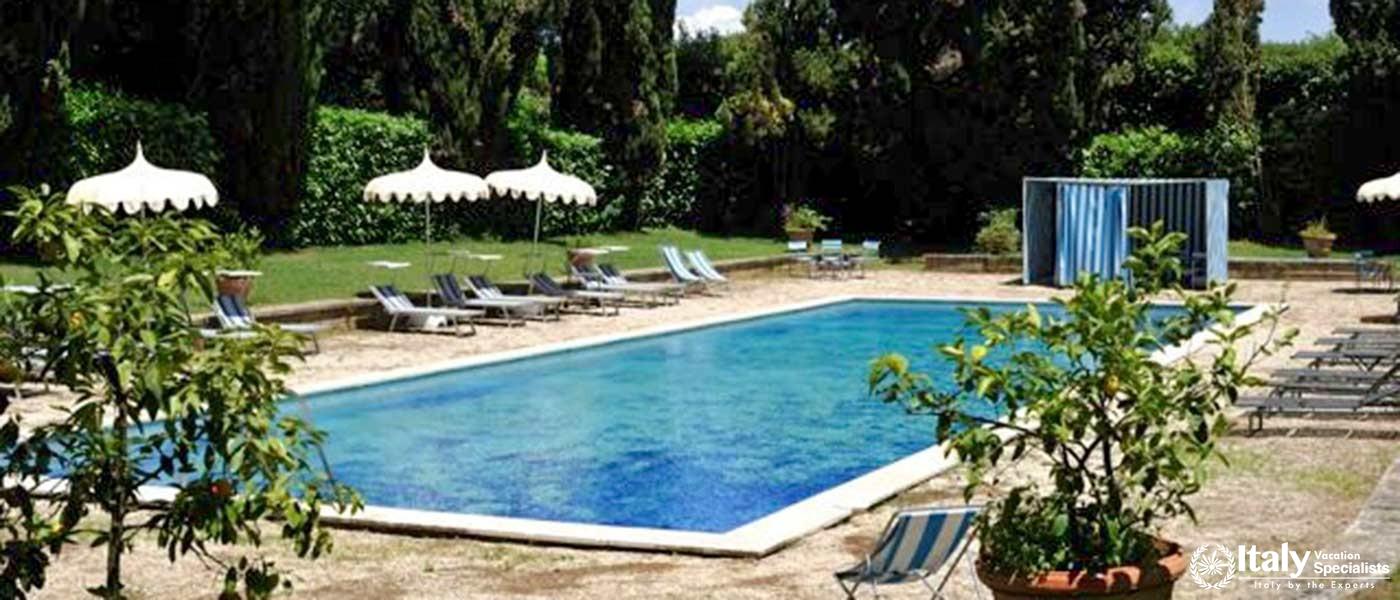 A large swimming pool surrounded by ancient chestnut trees.