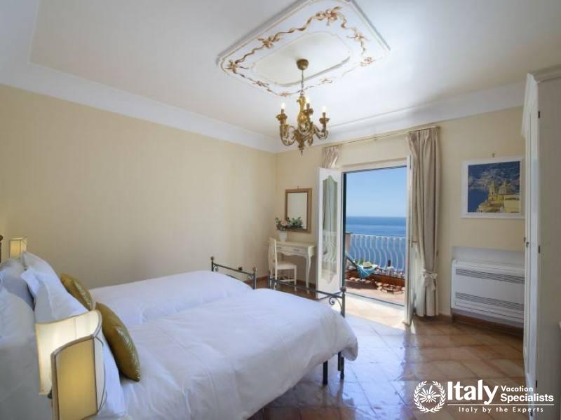 A charming double bedroom adorned with elegant furnishings, overlooking the sparkling Mediterranean.