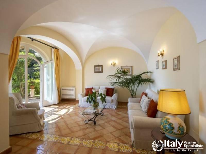 An elegant lounge area with cozy seating, soft lighting, and picturesque views of the villa\s garde