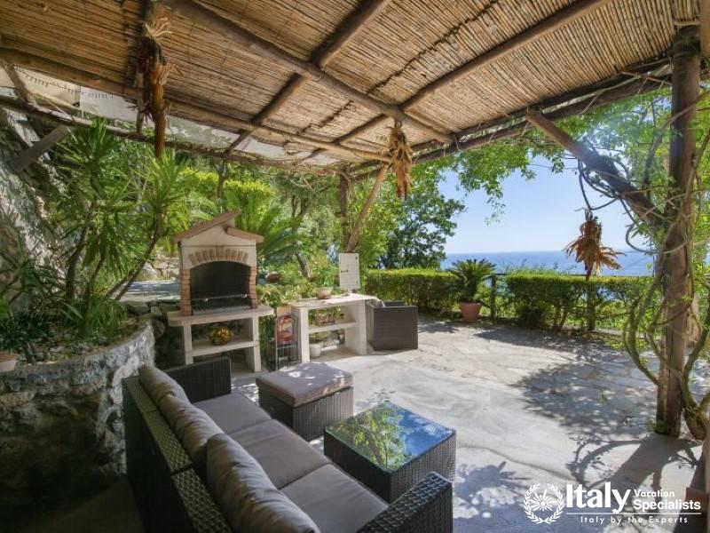 A shaded outdoor lounge with rustic charm and an enchanting view of the Mediterranean.