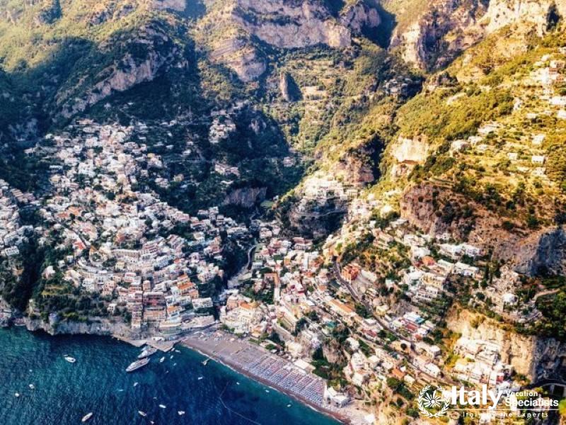 A dramatic aerial shot capturing the dense, colorful cascade of buildings in Positano down to the se
