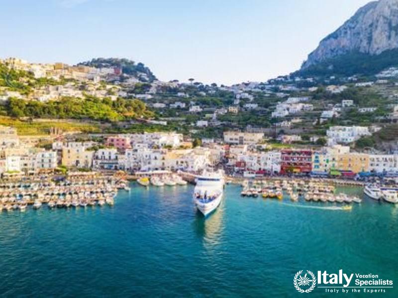 A lively harbor scene in Capri, with boats anchored in the blue waters and the town rising