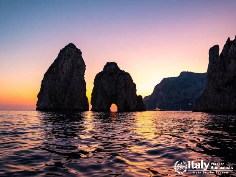 The iconic Faraglioni rock formations off the coast of Capri at sunset.