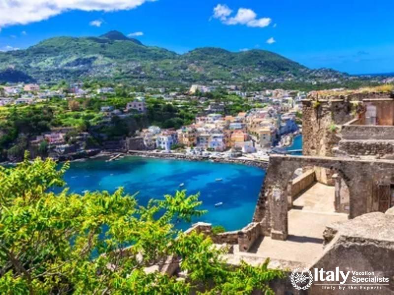 Vibrant coastal town of Ischia with clear blue waters and lush hills.