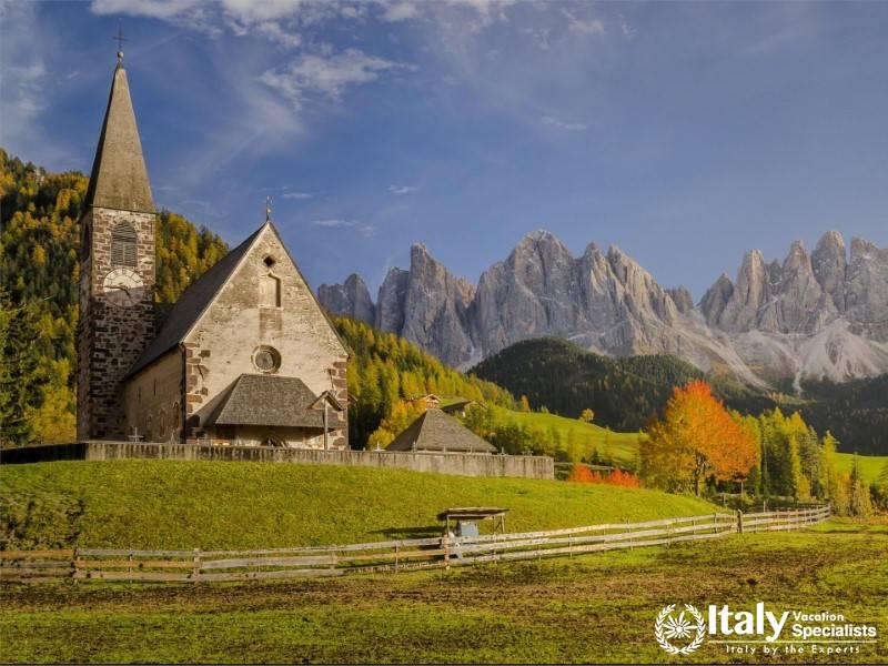 The charming St. Magdalena Church nestled in Val di Funes, framed by lush greenery.