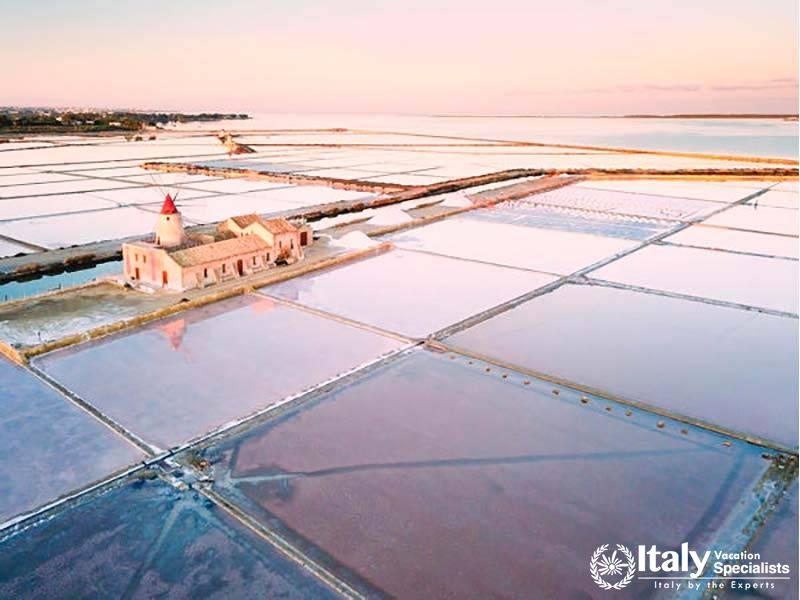 Stunning aerial view of expansive salt flats, with a lighthouse in the distance, captured during the