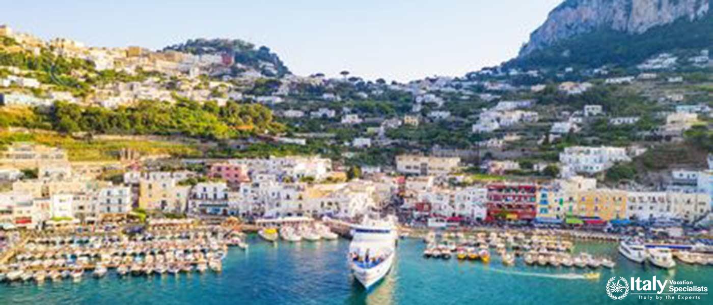 Vibrant and bustling harbor of Capri, filled with boats and surrounded by white-washed buildings.