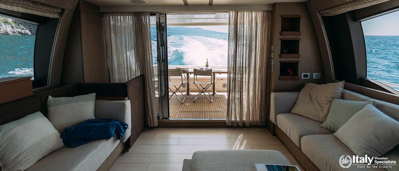 Interior of a luxury yacht cabin with open sliding doors leading to a deck overlooking the sea.