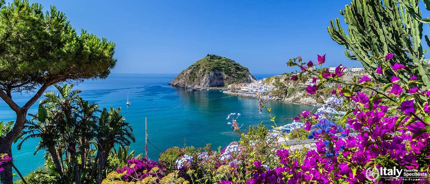 The picturesque harbor of Ischia, framed by lush vegetation and vibrant flowers with the Mediterrane