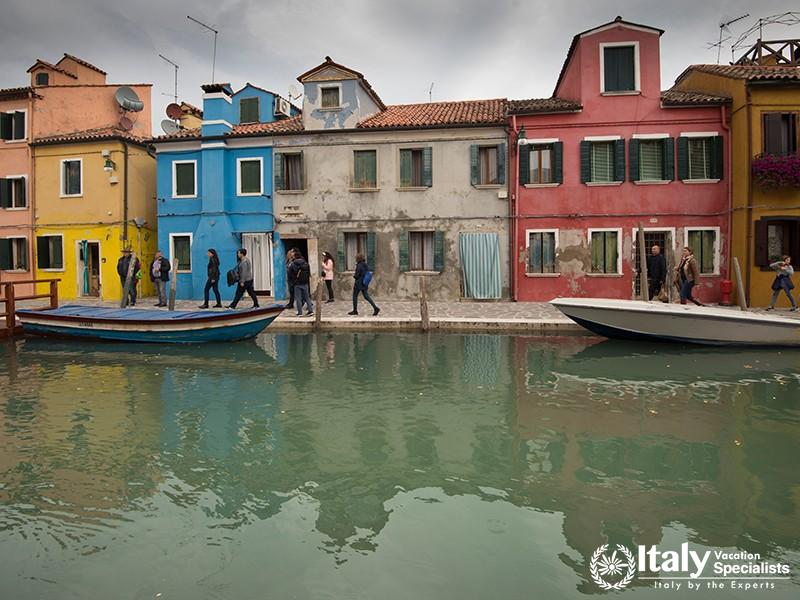 Burano, Italy, 27.10.2018 view of colourful houses and people walking on street of Burano with canal