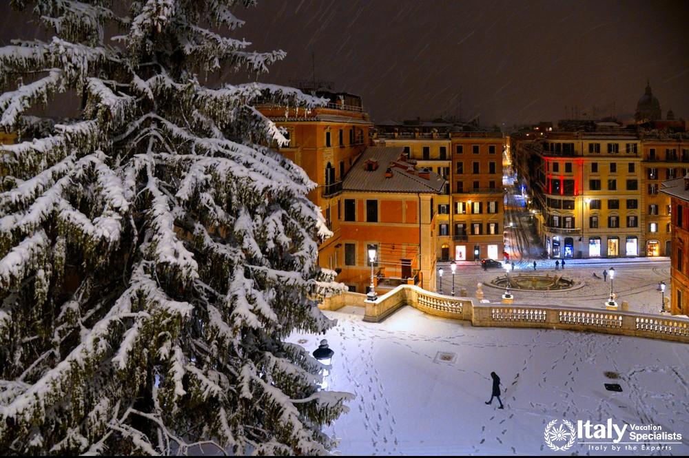 Night snowfall on Spanish square and steps in Rome with lonely person, old buildings and architectur